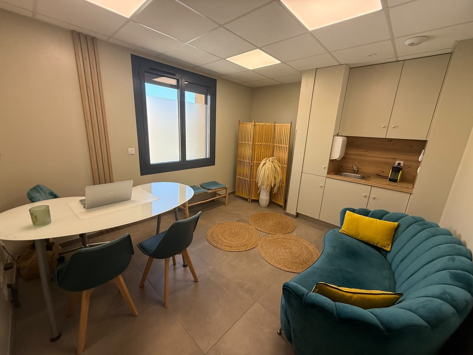 Le cabinet : table ronde, canapé bleu, tapis en fibres naturelles
