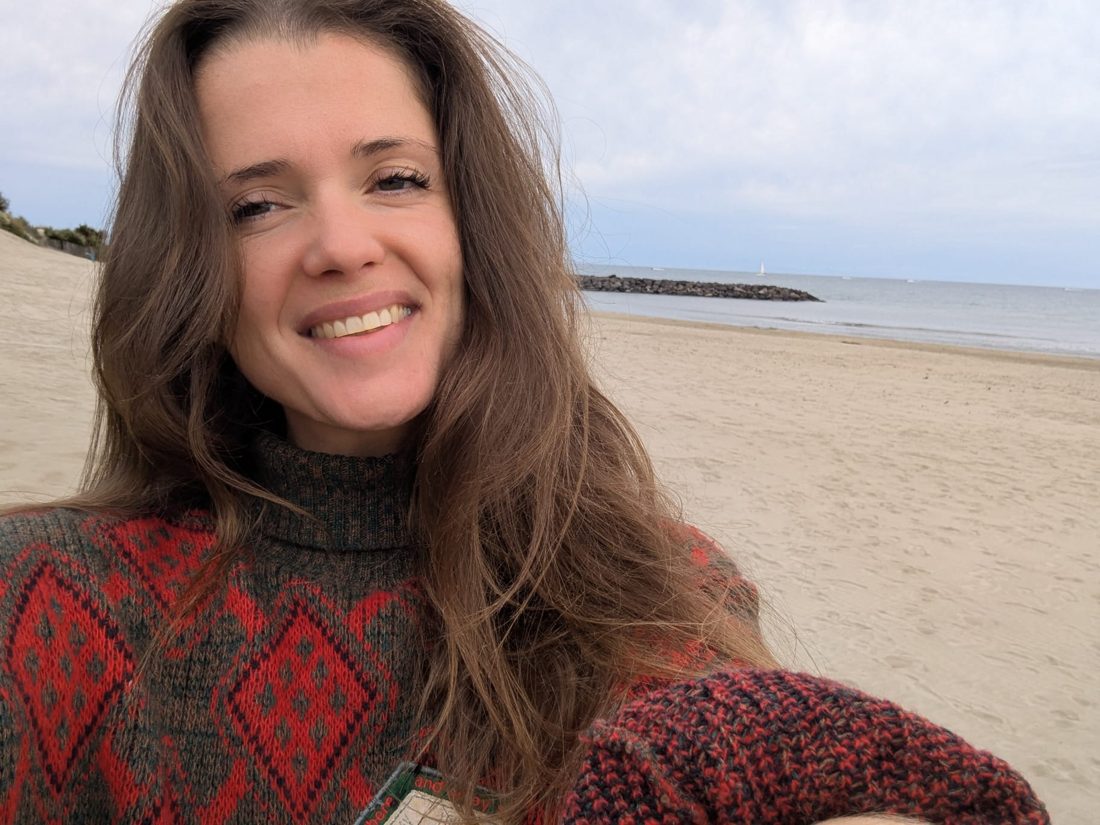 Portrait de Lola, éducatrice spécialisée, souriante au bord de la mer
